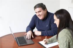 A male and female Comm Lab Fellow looking at a laptop together